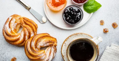 Tasse Kaffee mit Gebäck, Fruchtaufstrichen und Honig